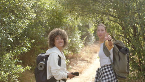Young-biracial-woman-with-curly-hair-and-a-young-Caucasian-woman-with-blonde-hair-are-hiking