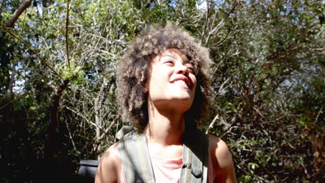 Young-biracial-woman-smiles-brightly,-surrounded-by-lush-greenery
