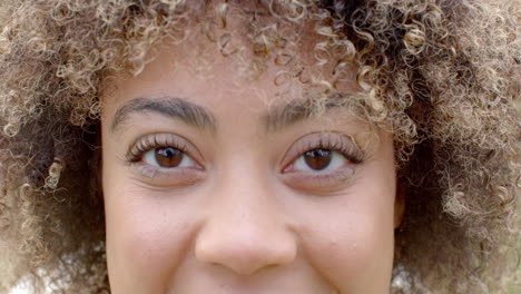 Close-up-of-a-young-biracial-woman-with-curly-hair-and-a-subtle-smile