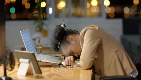 African-American-businesswoman-rests-her-head-on-a-desk-at-night,-with-copy-space