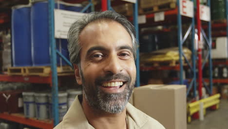 Animation-of-network-of-connections-with-icons-over-biracial-male-worker-smiling-in-warehouse