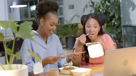Young-African-American-woman-and-biracial-woman-enjoy-a-business-meal-at-the-office