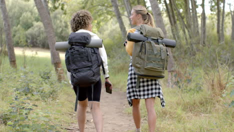 Two-women-with-backpacks-hike-along-a-forest-trail