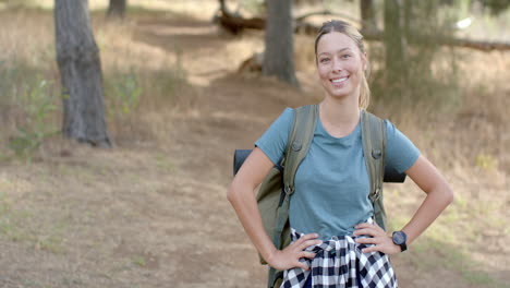 Young-Caucasian-woman-smiles-during-a-hike-in-the-woods-with-copy-space