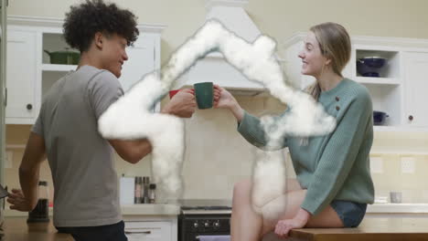 Animation-of-cloud-house-over-happy-diverse-couple-toasting-with-tea-cups-in-kitchen