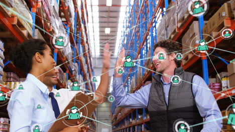 Animation-of-network-of-connections-with-icons-over-diverse-workers-high-fiving-in-warehouse