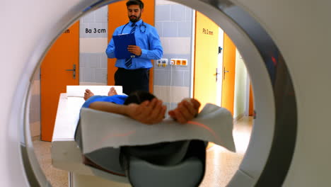 Doctor-reviewing-chart-of-patient-about-to-have-mri-scan
