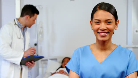Smiling-nurse-standing-with-arms-crossed-in-hospital