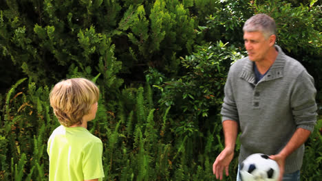 Father-and-son-playing-with-football-in-garden