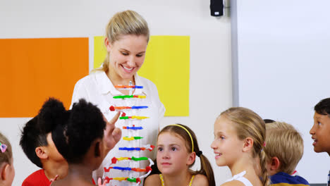 Teacher-assisting-school-kids-in-learning-abacus-in-classroom