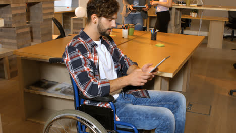 Male-business-executive-sitting-on-wheelchair-and-using-digital-tablet