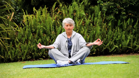 Grauhaarige-Frau-Macht-Yoga-Im-Garten