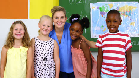 Portrait-of-teacher-and-kids-smiling-in-classroom
