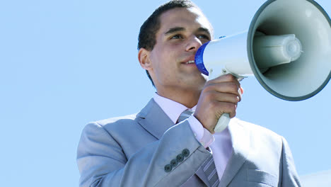 Businessman-shouting-through-a-megaphone-outdoors