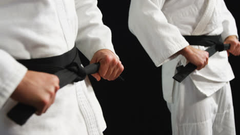 Men-in-black-belt-standing-against-black-background