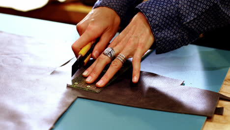 Mid-section-of-craftswoman-cutting-leather
