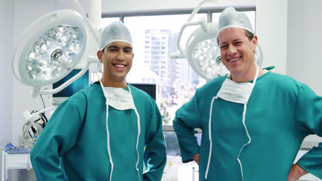 Portrait-of-male-surgeons-standing-with-hands-on-hips-in-operation-room