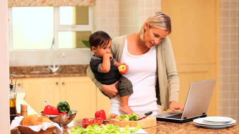 Madre-Lidiando-Con-El-Bebé-Mientras-Cocina-Y-Usa-Una-Computadora-Portátil