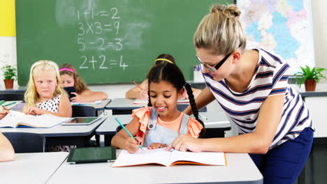 Teacher-helping-schoolgirl-with-their-homework-in-classroom