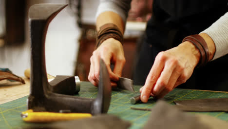 Mid-section-of-craftswoman-nailing-leather