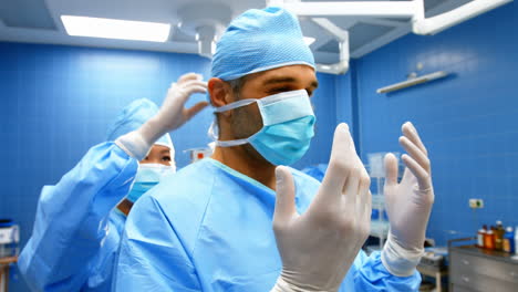 Enfermera-Ayudando-A-Un-Cirujano-A-Atar-Una-Mascarilla-Quirúrgica