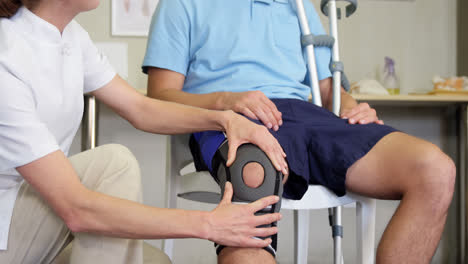 Physiotherapist-examining-patient's-knee