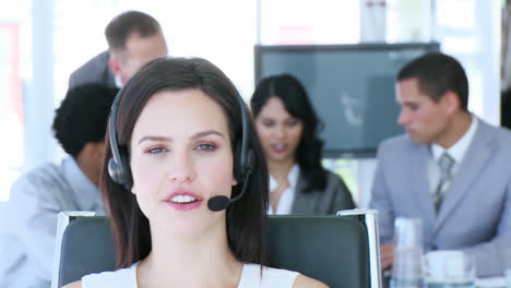 Portrait-of-businesswoman-talking-on-a-headset-in-front-of-her-team