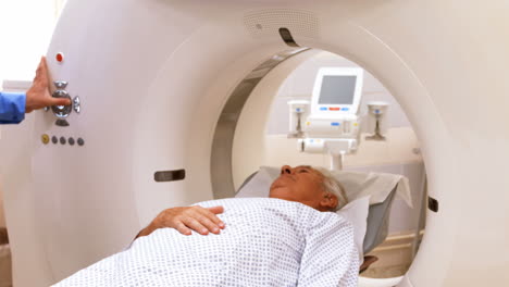 A-patient-is-loaded-into-an-mri-machine-while-doctor-and-nurse-watching