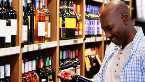 Man-looking-at-wine-bottle-in-grocery-section