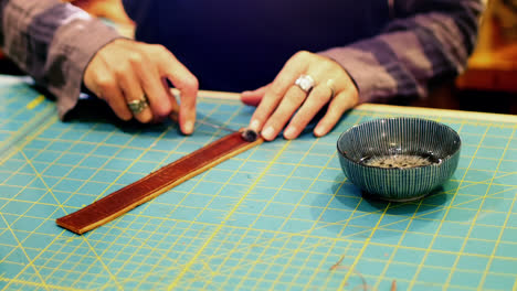 Mid-section-of-craftswoman-preparing-leather-belt