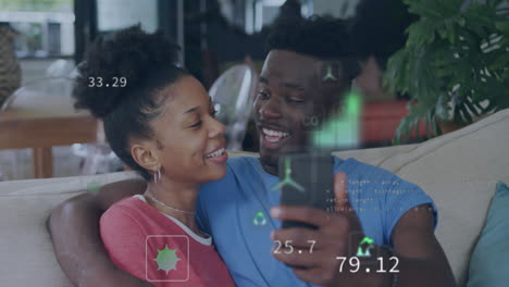 Animation-of-eco-icons-and-data-processing-over-happy-african-american-couple-using-smarthopne