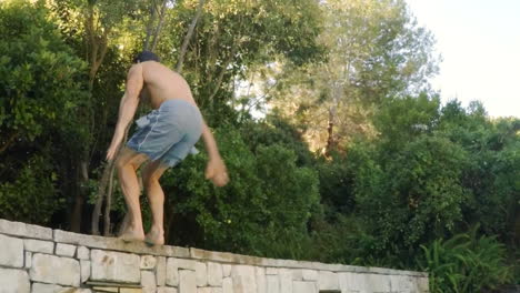 Young-man-performing-backflip-stunt-on-swimming-pool