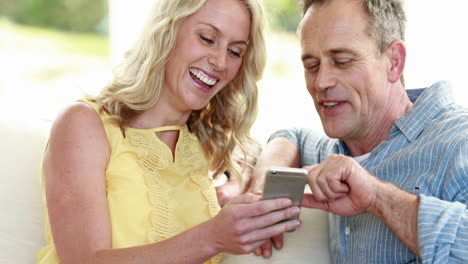 Glückliches-Paar-Mit-Smartphone-Auf-Dem-Sofa