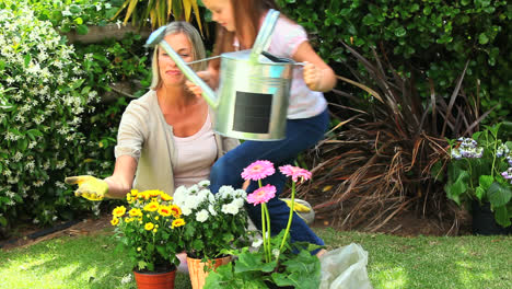 Mother-and-daughter-watering-potted-plants-in-the-garden