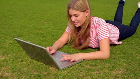 Smiling-woman-using-laptop-at-the-park