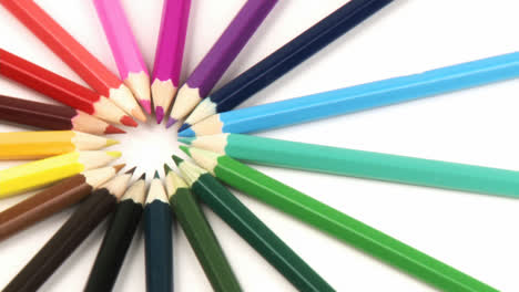 Close-up-of-colour-pencils-in-a-circle-turning-against-white