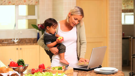 Mother-holding-baby-while-working-on-laptop