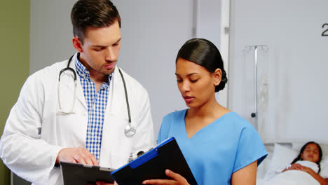 Nurse-and-doctor-discussing-over-clipboard