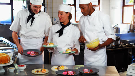 Three-chefs-placing-dessert-plates-on-counter