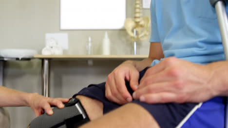 Physiotherapist-examining-patient's-knee