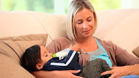 Mother-bottlefeeding-her-baby-on-sofa