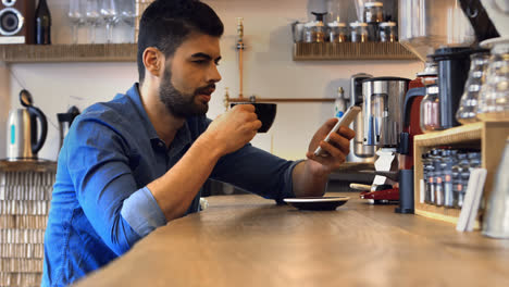 Male-business-executive-using-mobile-phone-while-having-coffee
