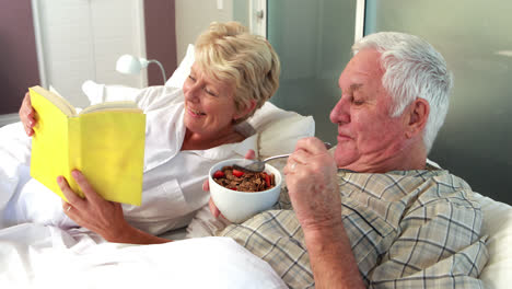 Senior-couple-reading-book-and-eating-cereal