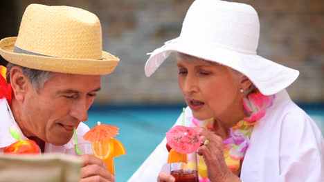 Senior-couple-with-garlands-drinking-colored-cocktails-