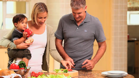 Father-preparing-vegetables-while-mother-holds-baby-