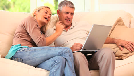 Couple-using-laptop-and-laughing