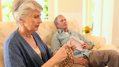 Retired-woman-knitting-while-her-husband-sleeps