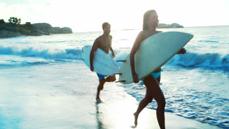 Couple-running-on-beach-with-surfboard