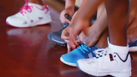 Girls-tying-shoe-laces-in-basketball-court