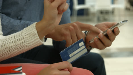Couple-with-smartphone-and-credit-card-discussing-